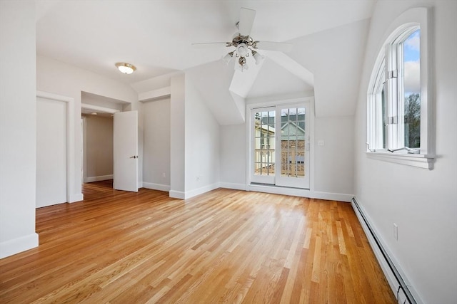 bonus room featuring ceiling fan, baseboard heating, light wood-style flooring, baseboards, and lofted ceiling