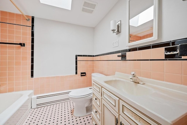 bathroom featuring a bath, a skylight, tile walls, a baseboard radiator, and toilet