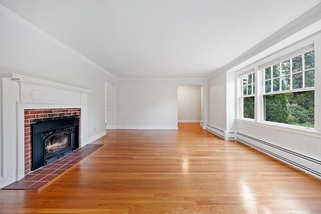 unfurnished living room with crown molding, arched walkways, light wood-style flooring, and a fireplace