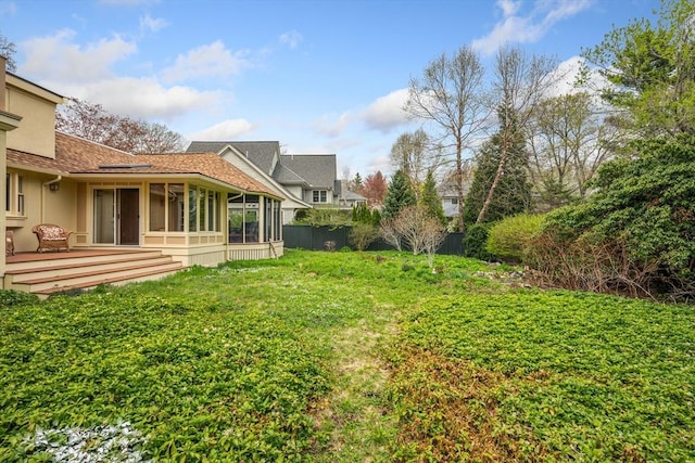 view of yard with fence, a wooden deck, and a sunroom