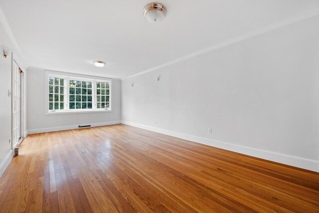unfurnished room featuring baseboards, visible vents, ornamental molding, and light wood-style flooring