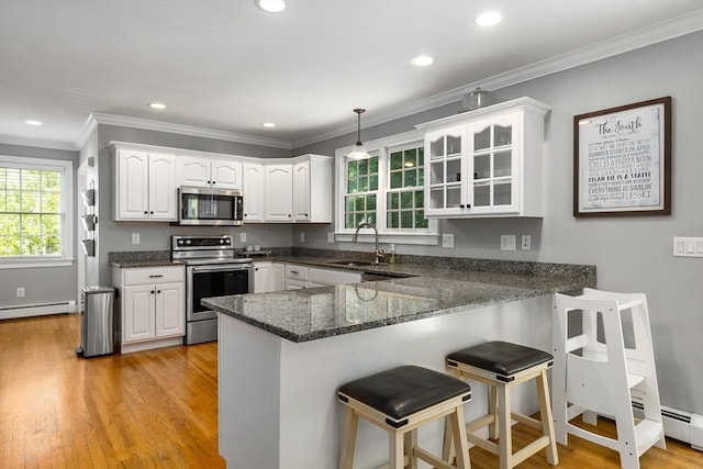 67 Madison St, Amesbury, MA 01913 - kitchen with stainless steel appliances, a peninsula, a breakfast bar area, white cabinets, and light wood-type flooring