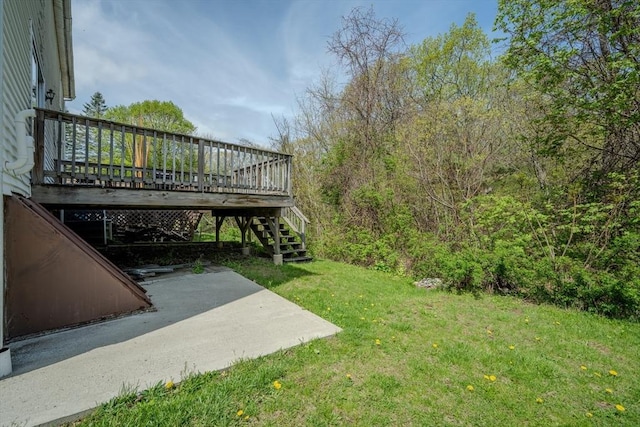 view of green lawn featuring a patio, a wooden deck, and stairs