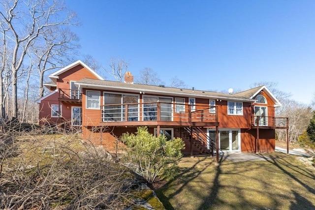 back of property featuring a yard, a chimney, and a wooden deck