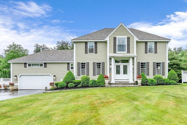 colonial home with french doors, a front lawn, and a garage