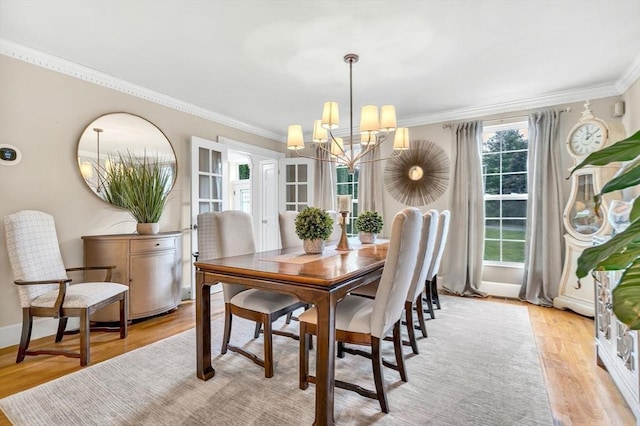 dining area with light hardwood / wood-style flooring, an inviting chandelier, and ornamental molding