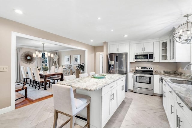 kitchen with an inviting chandelier, a kitchen breakfast bar, hanging light fixtures, appliances with stainless steel finishes, and a kitchen island