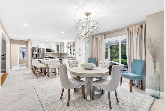 dining space with a chandelier, light parquet floors, and sink