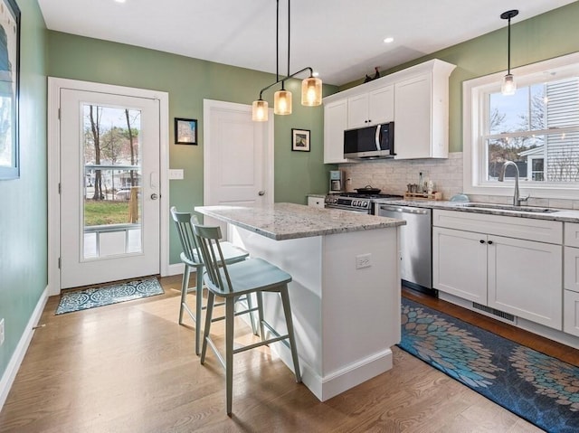 38 Oneil St, Hudson, MA 01749 - kitchen featuring appliances with stainless steel finishes, a sink, light wood-style floors, decorative backsplash, and a center island