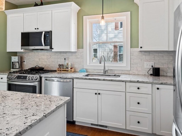 38 Oneil St, Hudson, MA 01749 - kitchen featuring appliances with stainless steel finishes, a sink, white cabinets, backsplash, and pendant lighting