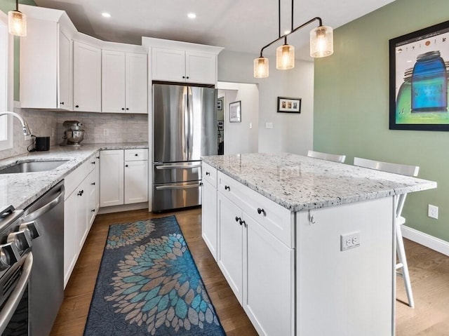 38 Oneil St, Hudson, MA 01749 - kitchen featuring appliances with stainless steel finishes, a sink, dark wood-style flooring, backsplash, and white cabinetry