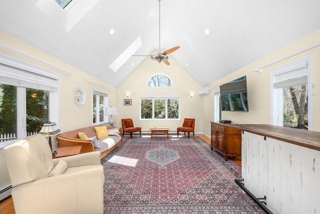 interior space featuring a skylight, high vaulted ceiling, a ceiling fan, and a baseboard heating unit
