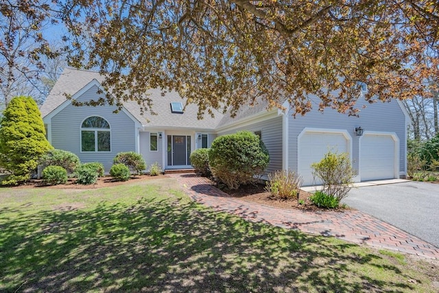 traditional-style home featuring a garage, a front lawn, driveway, and a shingled roof