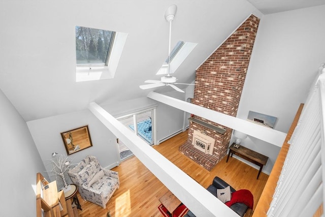 interior space featuring a ceiling fan, high vaulted ceiling, wood finished floors, and a skylight