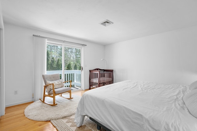 bedroom with light wood-style floors, baseboards, access to outside, and visible vents
