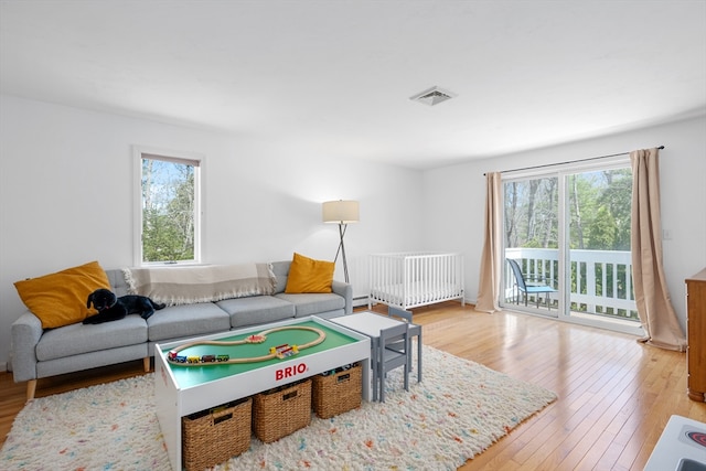 living area featuring a healthy amount of sunlight, hardwood / wood-style flooring, and visible vents