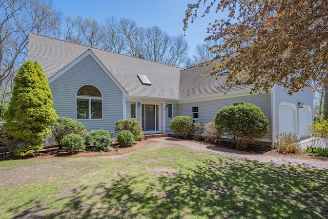 ranch-style home featuring roof with shingles and a front lawn