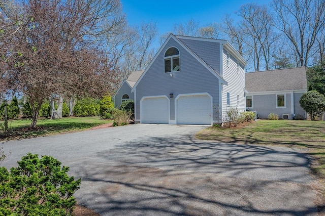 view of side of property featuring a lawn, an attached garage, and aphalt driveway