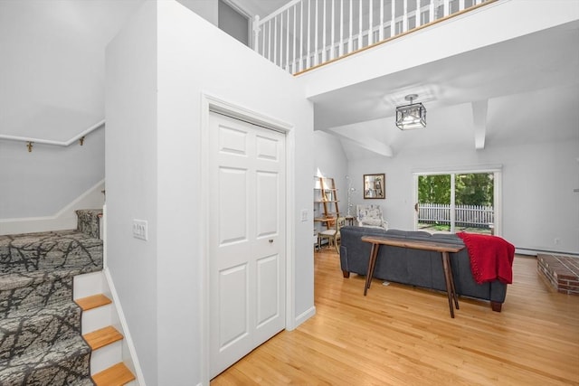 interior space featuring baseboard heating, baseboards, wood finished floors, and stairway