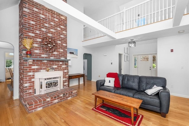 living area with baseboards, arched walkways, a high ceiling, and wood finished floors