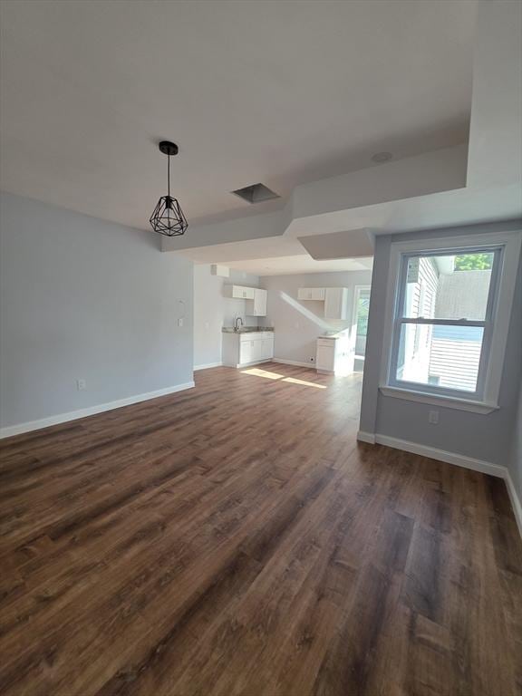 unfurnished living room featuring dark wood-type flooring and baseboards