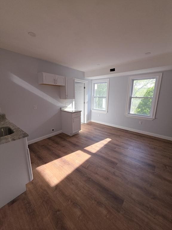 unfurnished living room with baseboards, dark wood-type flooring, and a sink