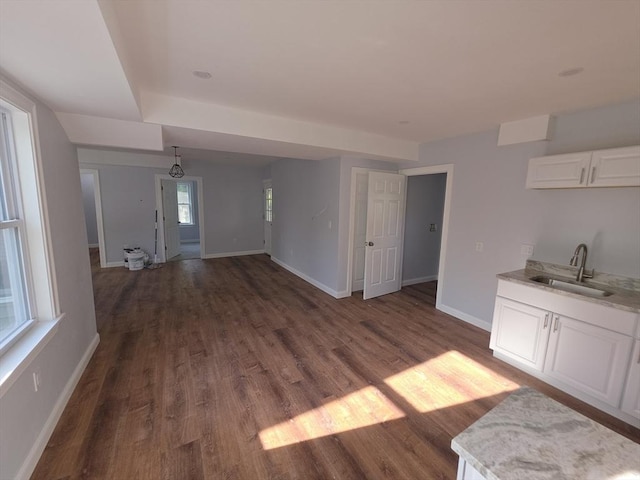 unfurnished dining area with a sink, dark wood-style floors, and baseboards