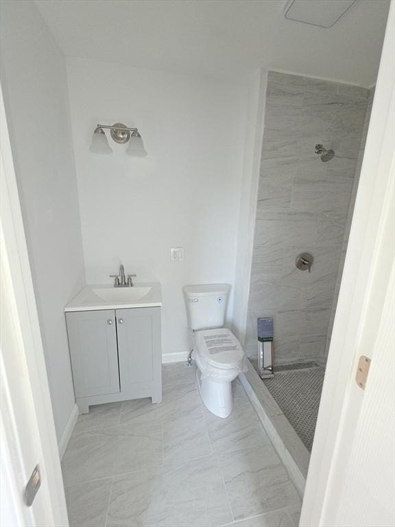 bathroom with a shower stall, toilet, baseboards, and vanity
