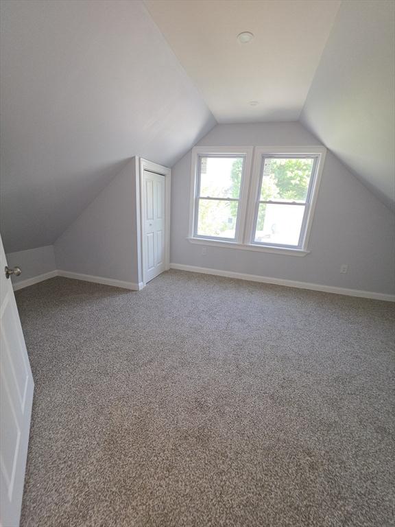 bonus room with carpet flooring, lofted ceiling, and baseboards