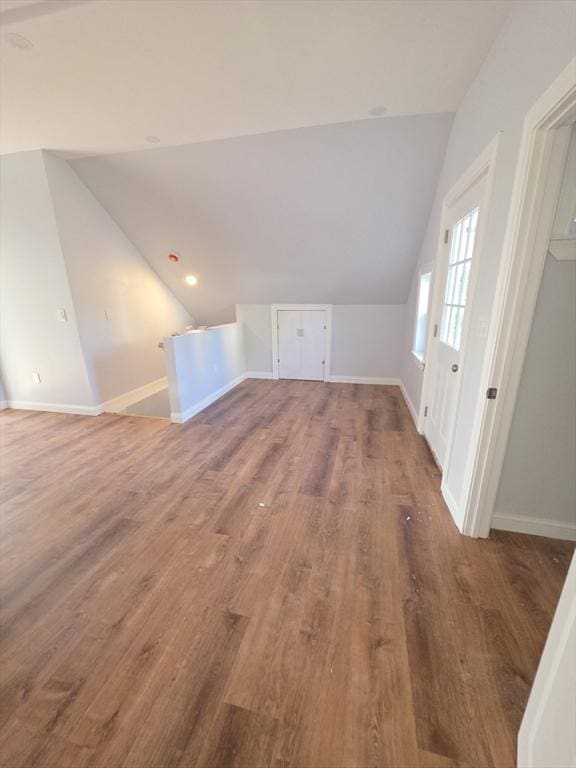 additional living space with vaulted ceiling, wood finished floors, and baseboards