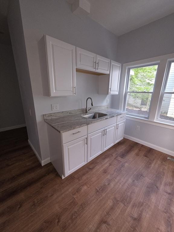 kitchen featuring a sink, baseboards, white cabinetry, and dark wood-type flooring