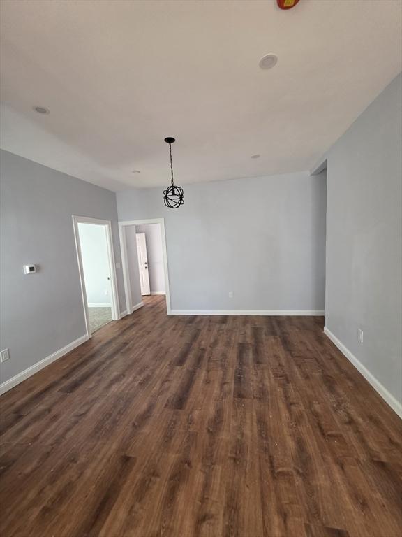 empty room with dark wood-type flooring and baseboards