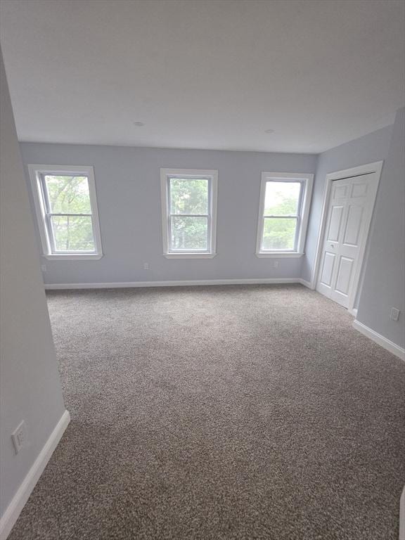 unfurnished room featuring carpet and baseboards