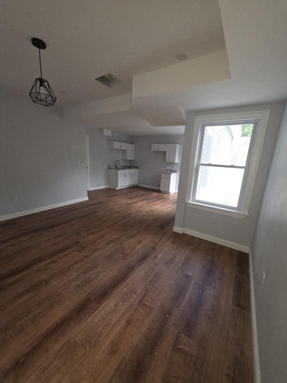unfurnished living room featuring baseboards and dark wood-style flooring