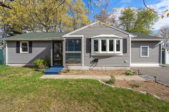 view of front of house featuring a shingled roof and a front lawn