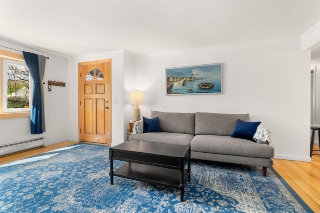 living area with crown molding, a baseboard radiator, baseboards, and wood finished floors