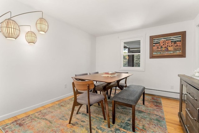 dining area featuring baseboards, a baseboard heating unit, and light wood finished floors