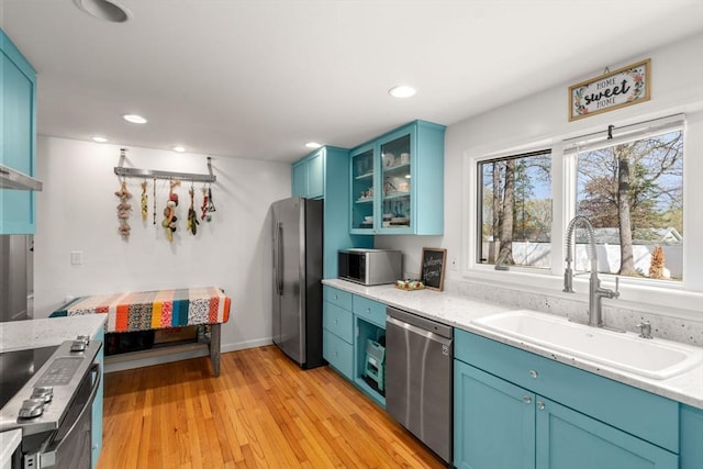 kitchen featuring a sink, appliances with stainless steel finishes, and blue cabinets
