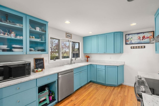 kitchen with a sink, light wood finished floors, blue cabinets, and stainless steel appliances