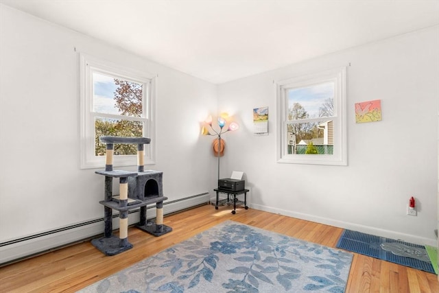 interior space with baseboards, a baseboard heating unit, and wood finished floors