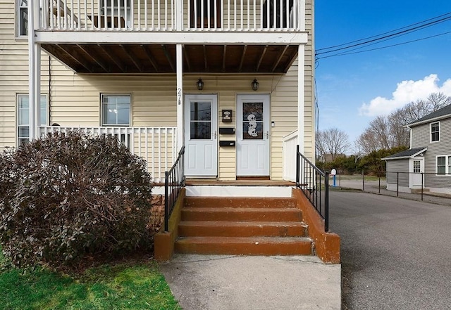 view of exterior entry featuring a balcony and covered porch