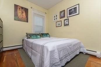 bedroom with baseboards, a baseboard radiator, and wood finished floors