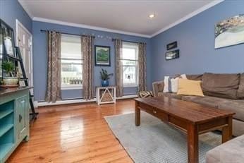 living area with crown molding, recessed lighting, and wood finished floors