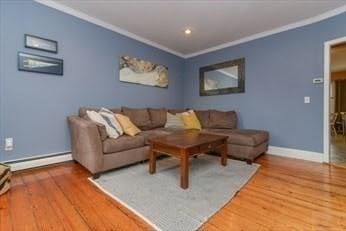 living area featuring crown molding, a baseboard heating unit, and wood finished floors