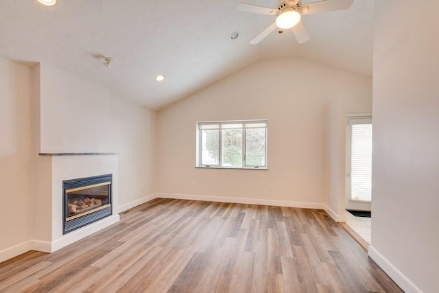 unfurnished living room featuring wood finished floors, a glass covered fireplace, vaulted ceiling, recessed lighting, and ceiling fan