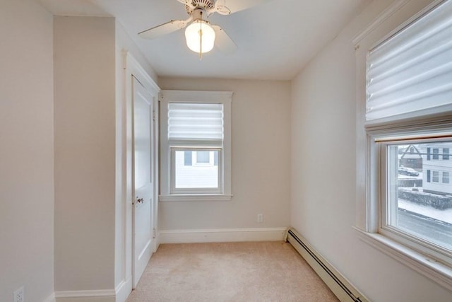 empty room featuring a baseboard radiator, light colored carpet, ceiling fan, and baseboards