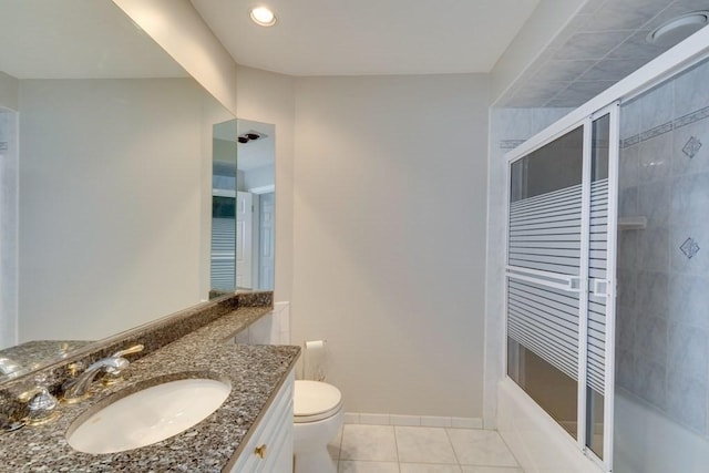 bathroom featuring tile patterned flooring, toilet, vanity, bath / shower combo with glass door, and baseboards