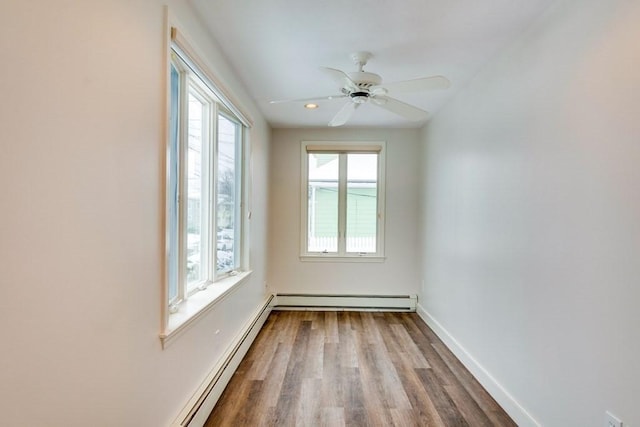 spare room with baseboard heating, healthy amount of natural light, dark wood-type flooring, baseboards, and recessed lighting