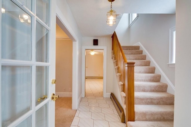 stairway with a baseboard radiator, tile patterned flooring, and baseboards