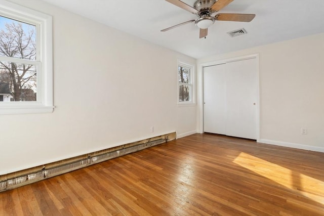 empty room featuring hardwood / wood-style floors, ceiling fan, and baseboard heating